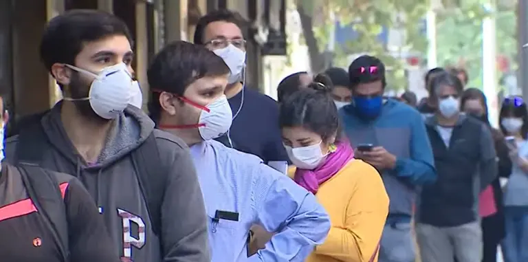 Personas hacen cola con mascarillas