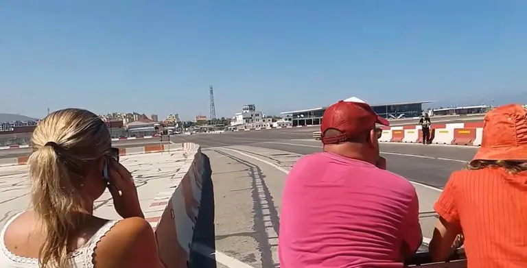 Peatones esperando el paso de un avi&oacute;n en el aeropuerto