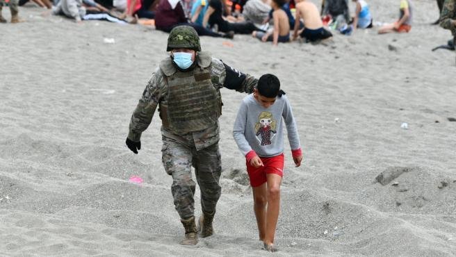 Un militar acompaña a un niño procedente de Marruecos en Ceuta el pasado verano