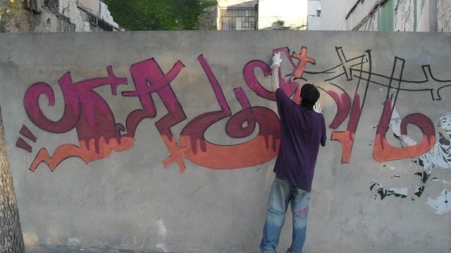 Un graffitero haciendo una pintada en un muro