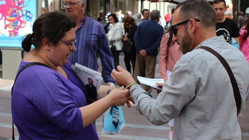 Una militante de Adelante Algeciras colocando una pulsera a un viandante