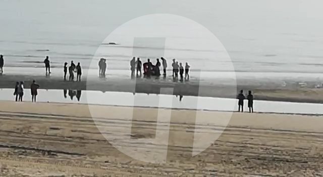 Usuarios de la playa atienden al hombre tendido en la orilla