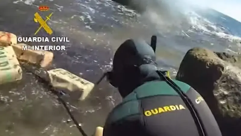 Un agente saca del agua varios fardos