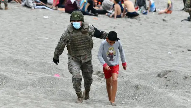 Un militar acompa&ntilde;a a un ni&ntilde;o procedente de Marruecos en Ceuta el pasado verano