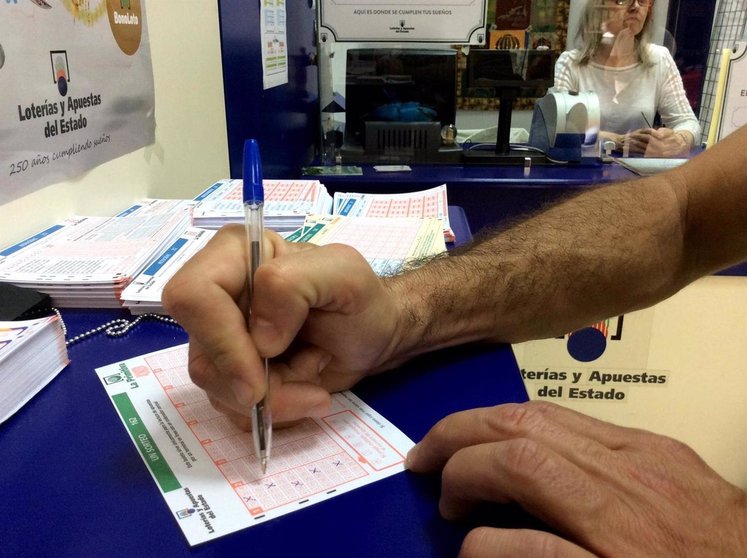 Un hombre rellena un boleto de lotería, en una foto de archivo